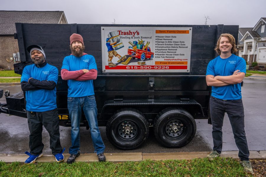 junk removal pros in front of trashys hauling truck